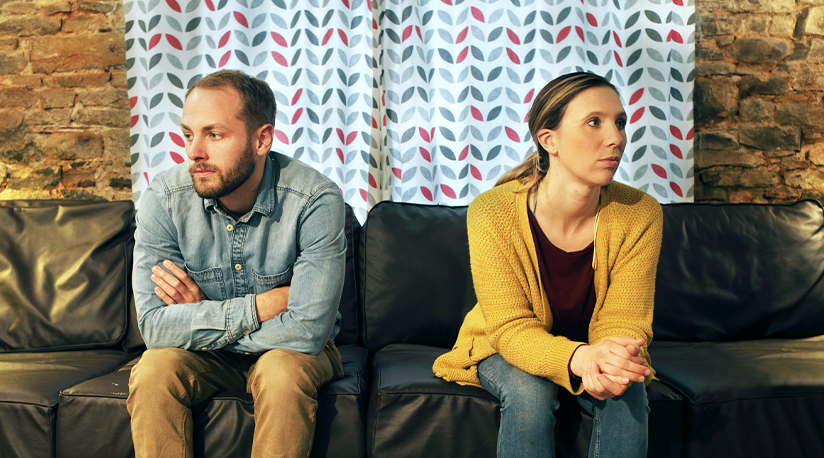 Man and woman sitting on couch facing away from each other